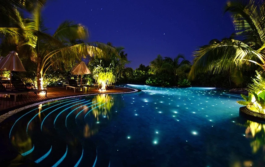 Piscina iluminada com refletores subaquáticos Cristal Led Inox criando efeito céu estrelado em ambiente noturno.